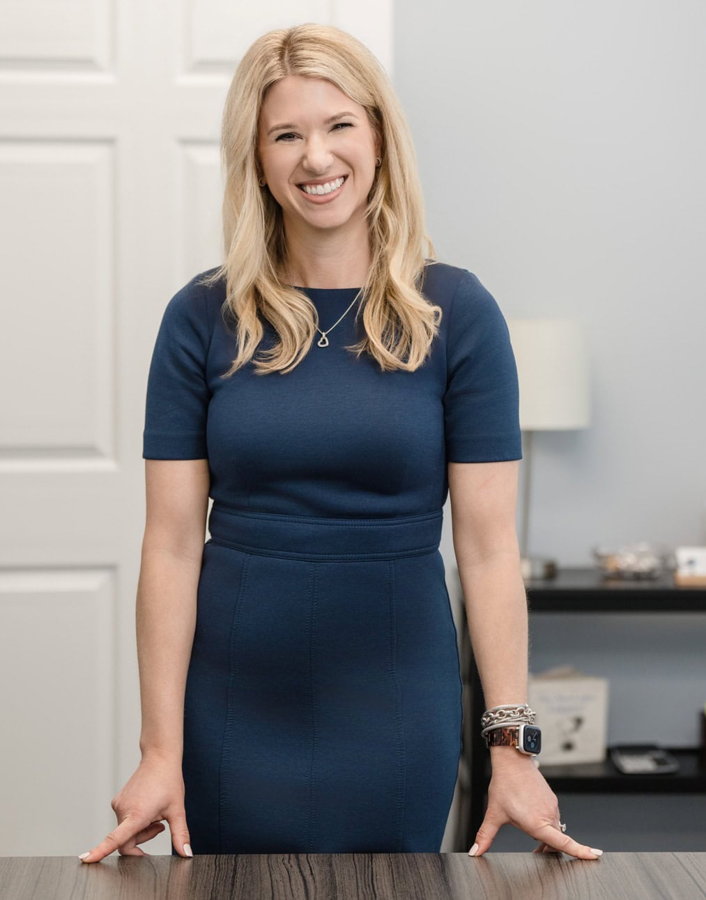 Raleigh Family Law Attorney Sarah Privette stands at her desk to warmly greet a victim of domestic abuse.