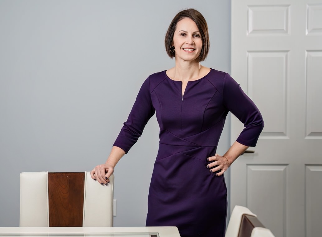 Raleigh Divorce Attorney Katherine Frye stands next to a chair in her Wake County office.